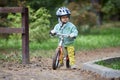 Child on a running balance bike on an autumn or summer cold day. Mittens on the hands Royalty Free Stock Photo