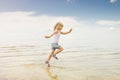 Child running beach shore splashing water