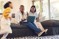 Child running with stressed parents on a laptop at their home in the living room with problems. Upset, technology and Royalty Free Stock Photo