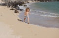 Child running through water close to shore along the sea beach. A boy runs along the sea coast. Rest of children on Royalty Free Stock Photo