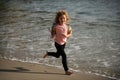 Child running through water close to shore along the sea beach. A boy runs along the sea coast. Rest of children on Royalty Free Stock Photo