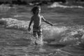 Child running through water close to shore along the sea beach. A boy runs along the sea coast. Rest of children on