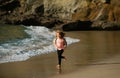 Child running through water close to shore along the sea beach. A boy runs along the sea coast. Rest of children on Royalty Free Stock Photo