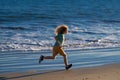 Child running through water close to shore along the sea beach. A boy runs along the sea coast. Rest of children on Royalty Free Stock Photo
