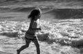 Child running through water close to shore along the sea beach. A boy runs along the sea coast. Rest of children on Royalty Free Stock Photo