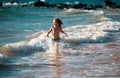 Child running through water close to shore along the sea beach. A boy runs along the sea coast. Rest of children on Royalty Free Stock Photo