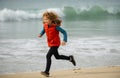 Child running through water close to shore along the sea beach. A boy runs along the sea coast. Rest of children on Royalty Free Stock Photo