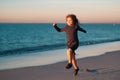 Child running through water close to shore along the sea beach. A boy runs along the sea coast. Rest of children on Royalty Free Stock Photo