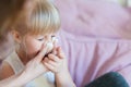 Child with runny nose. Mother helping to blow kid`s nose with paper tissue. Seasonal sickness Royalty Free Stock Photo