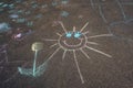 Child`s crayon drawing of sun and flower on asphalt. Royalty Free Stock Photo