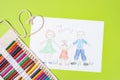 Child`s drawing of a family. Mom, dad and child are drawn with pencils on a sheet of paper on a green background Royalty Free Stock Photo