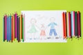 Child`s drawing of a family. Mom, dad and child are drawn with pencils on a sheet of paper on a green background Royalty Free Stock Photo