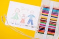Child`s drawing of a family. Mom, dad and child are drawn with pencils on a sheet of paper on a yellow background Royalty Free Stock Photo