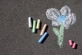 Child`s drawing of flower and colorful chalks on a street.