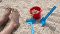 Child's feet full of sand playing with shovels and plastic buckets Royalty Free Stock Photo
