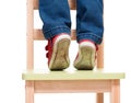 Child's feet standing on the little chair on tiptoes