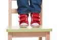 Child's feet standing on the little chair on tiptoes