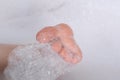 Child`s foot in soapy foam. Taking a bath, hygiene procedures