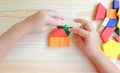 A child\'s hand constructs a house using multicolored wooden blocks and construction figures. A close-up of multicolored wooden Royalty Free Stock Photo