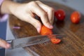 child's hand cuts a cherry tomato into slices on board