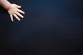 Child's hand on a dark background