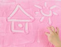 Child`s hand draws house and sun on the sand. Royalty Free Stock Photo