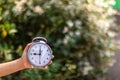 Child`s hand holding alarm clock on green blurred background. Royalty Free Stock Photo