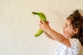 Little girl holding a banana in her hands.