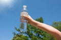 A child& x27;s hand is holding a bottle of drinking water against the blue sky Royalty Free Stock Photo