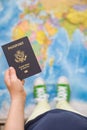 Child`s hand holding US passport. Map background. Ready for traveling. Open world Royalty Free Stock Photo