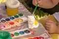 Child's hand holds a brush and paints a plaster figure.