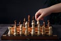 Child`s hand holds a chess piece. Chess game on a dark background