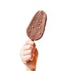 A child`s hand holds a chocolate ice cream on a stick, a popsicle with nuts, isolated on a white background Royalty Free Stock Photo