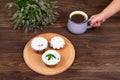 A child`s hand holds a cup of tea and mint near the board with muffins with black currant, on a background of flowers