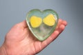 A child`s hand holds handmade soap in the form of a heart on a blue background Royalty Free Stock Photo