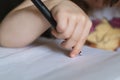 A child`s hand holds a large black ballpoint pen and draws on a white piece of paper. Selective focus. A little three-year-old gir Royalty Free Stock Photo