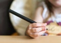 A child`s hand holds a large black ballpoint pen and draws on a white piece of paper.A three-year-old girl learns to hold a pen an Royalty Free Stock Photo