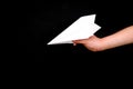 A child& x27;s hand holds a paper airplane on a black background.The theme of travel. Royalty Free Stock Photo