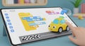 Child s hand interacting with a tablet displaying a coding interface and a toy car Royalty Free Stock Photo