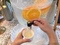 The child`s hand is opening the water from the jar that has lemons floating.