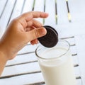 Child's hand with Oreo cookies extends to milk