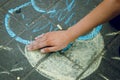 A child`s hand paints the sun and the asphalt with chalk. Amusement park.