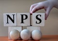 A child's hand places a large cube next to other cubes. NPS acronym concept