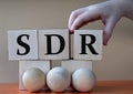 A child's hand places a large cube next to other cubes. SDR acronym concept Royalty Free Stock Photo