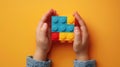 A child\'s hand playing with Lego. There are Legos scattered on the table with a orange background