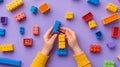 A child\'s hand playing with Lego. There are Legos scattered on the table with a purple background