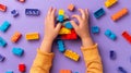 A child\'s hand playing with Lego. There are Legos scattered on the table with a purple background