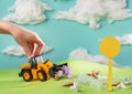 Child`s hand playing with a toy truck collecting garbage over the lawn Royalty Free Stock Photo