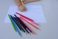 The child`s hand preparing to write on a white sheet of paper with colored pencils. Education and children activities concept Royalty Free Stock Photo