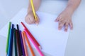 The child`s hand preparing to write on a white sheet of paper with colored pencils.  Education and children activities concept Royalty Free Stock Photo